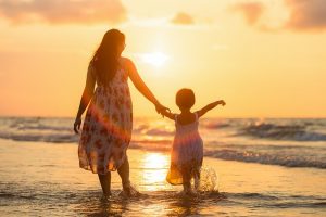 Mother and daughter enjoying sunset on the beach.