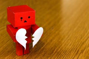 A paper figure holding a broken heart