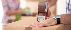packing services Florida - man taping a moving box