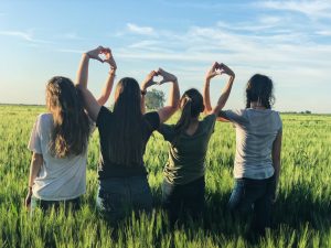 Find a roommate in Deerfield Beach FL- Four girls sitting on the grass making a hart shape with their hands
