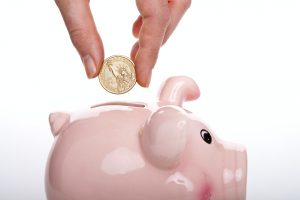 A woman putting a coin into a piggy bank