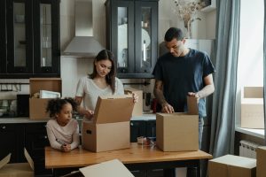 A family of three, mother, father and daughter unpacking their moving boxes in the kitchen