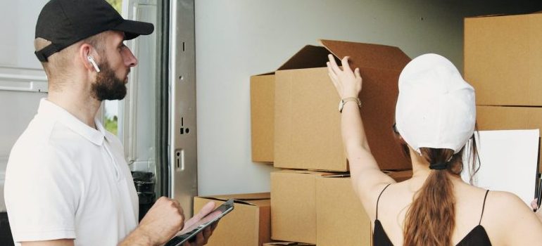 two people packing cardboard boxes in the moving truck
