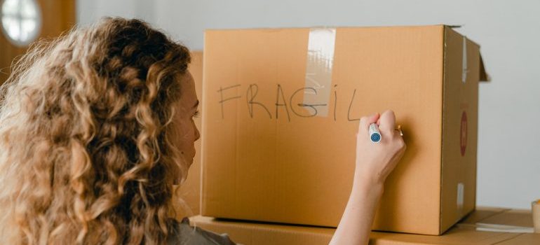 Woman writing note on carton box with marker
