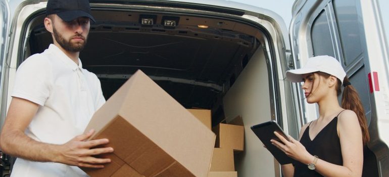 male and female loading a van with cardboard boxes