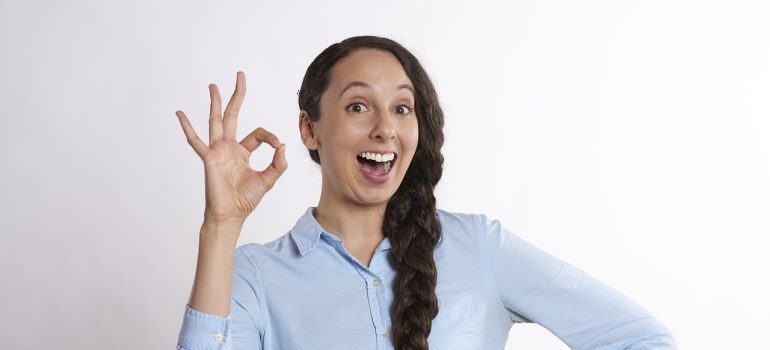 Smiling woman showing a-ok sign.