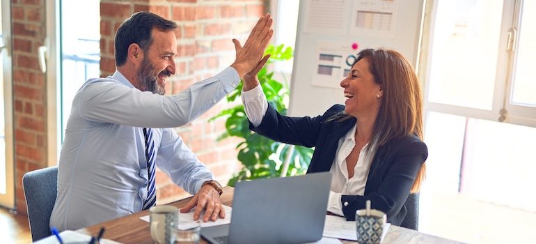 man and a woman high fiving in an office