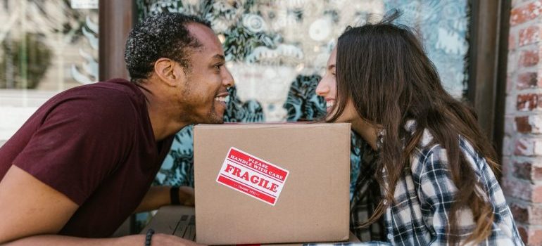 two people leaning on a cardboard box