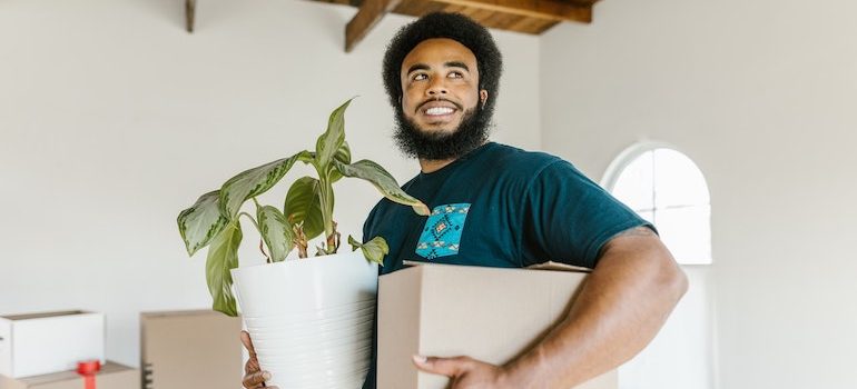 Man holding a box and a plant