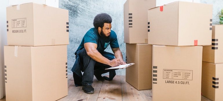 man surrounded by boxes taking notes is part of commercial movers Clearwater
