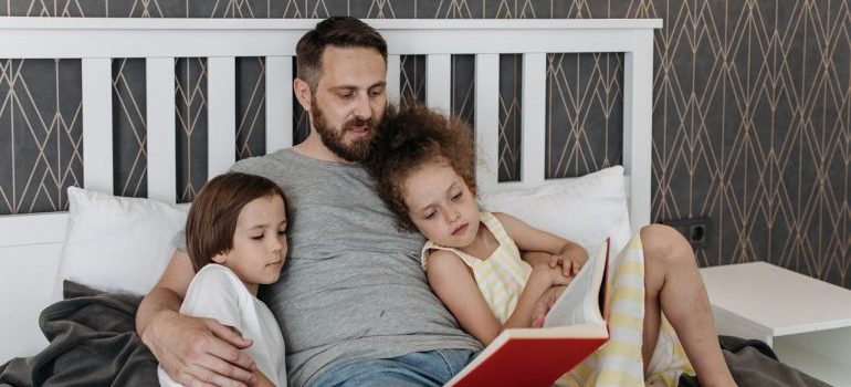 A man reads to children on the bed