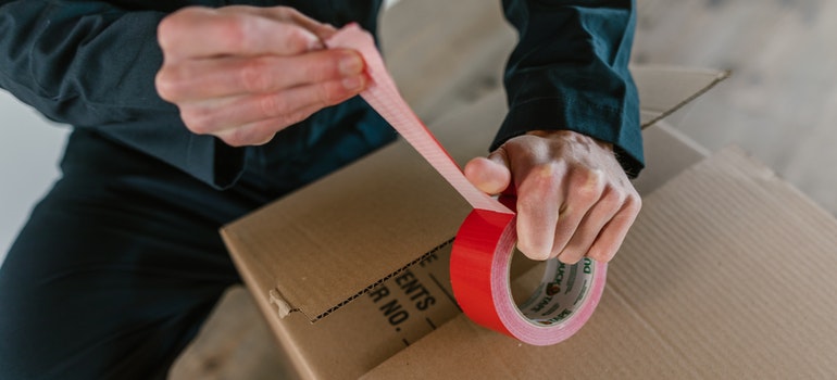 mover sealing a moving box - organize and store holiday decorations