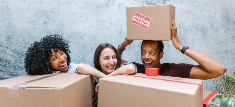 Women and man surrounded by boxes smiling.