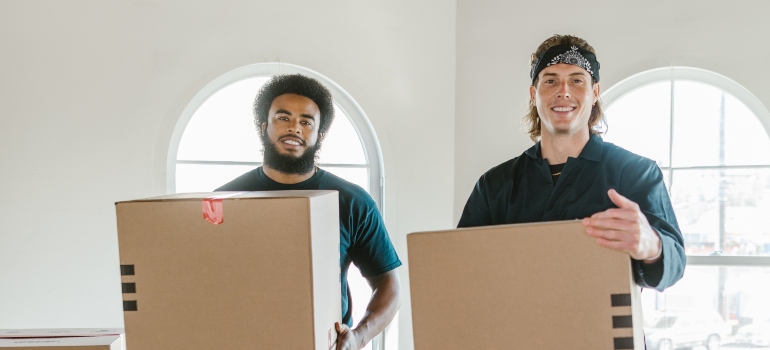 two movers holding packing boxes