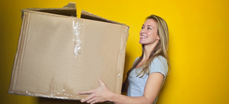 a woman holding a box in front of a yellow background
