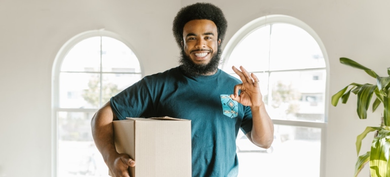 A mover holding a box and thumbs up
