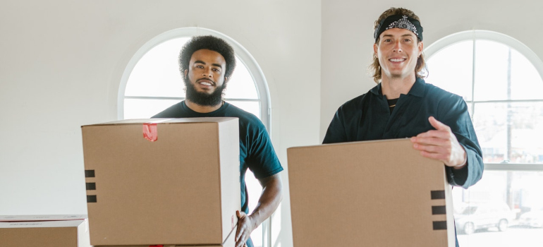 Two movers holding moving boxes.